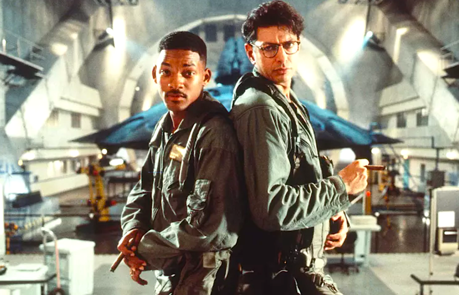 two men in military jumpsuits in front of an alien ship