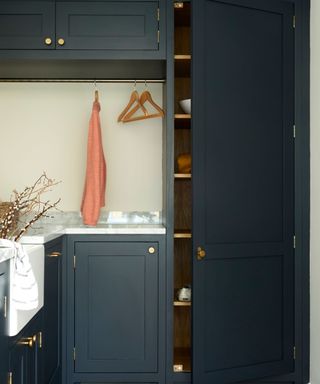 Intense, dark shades on laundry room cabinets, with hanging rail above marble counter