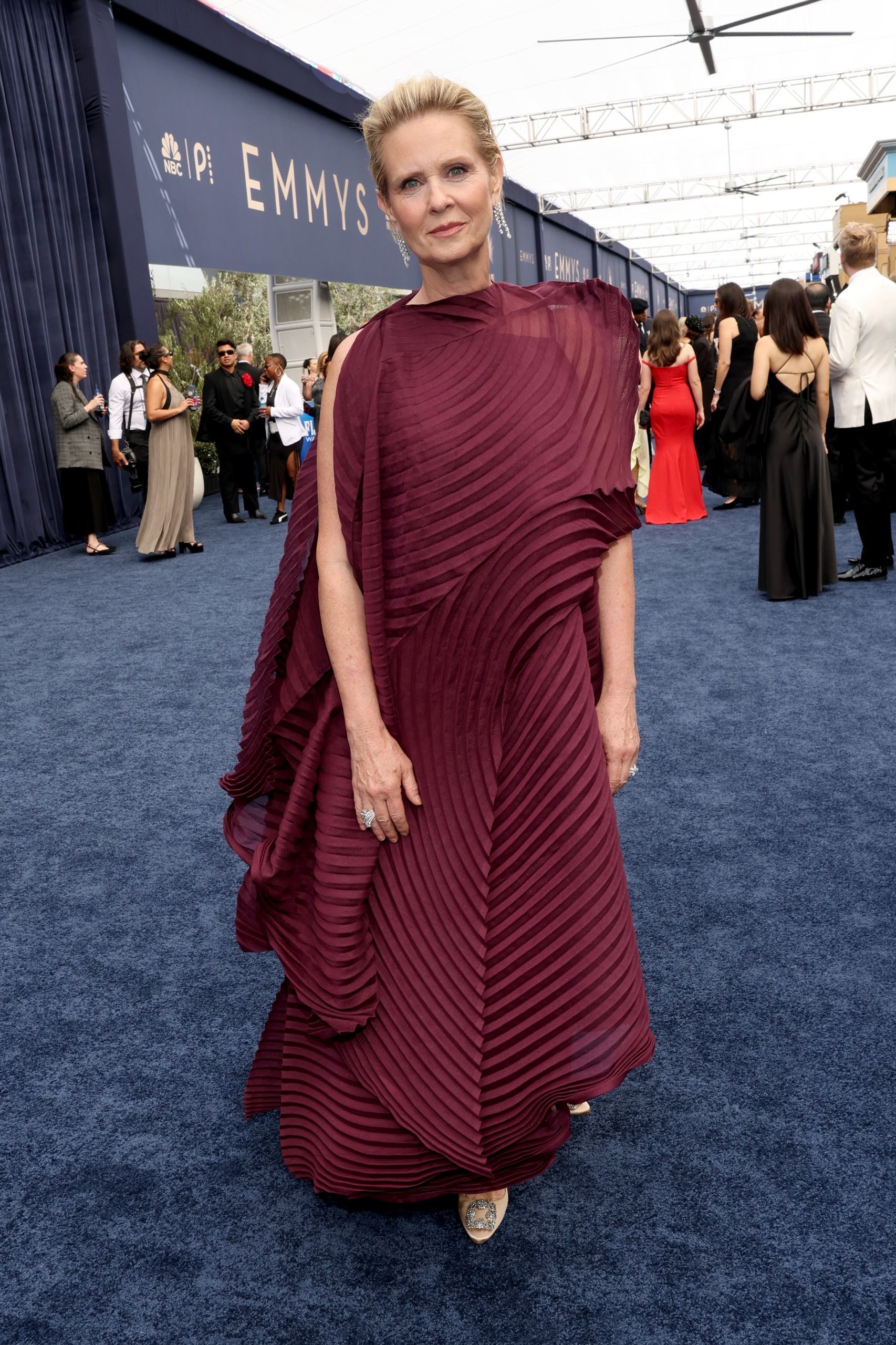 a blonde woman in a red gown on the blue emmys carpet