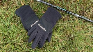 Columbia Fast Trek III Fleece Gloves on the grass next to a trekking pole