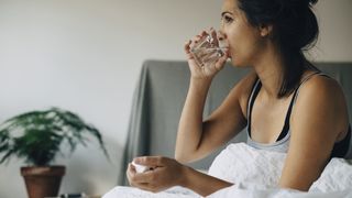 Person drinking water while sat in bed