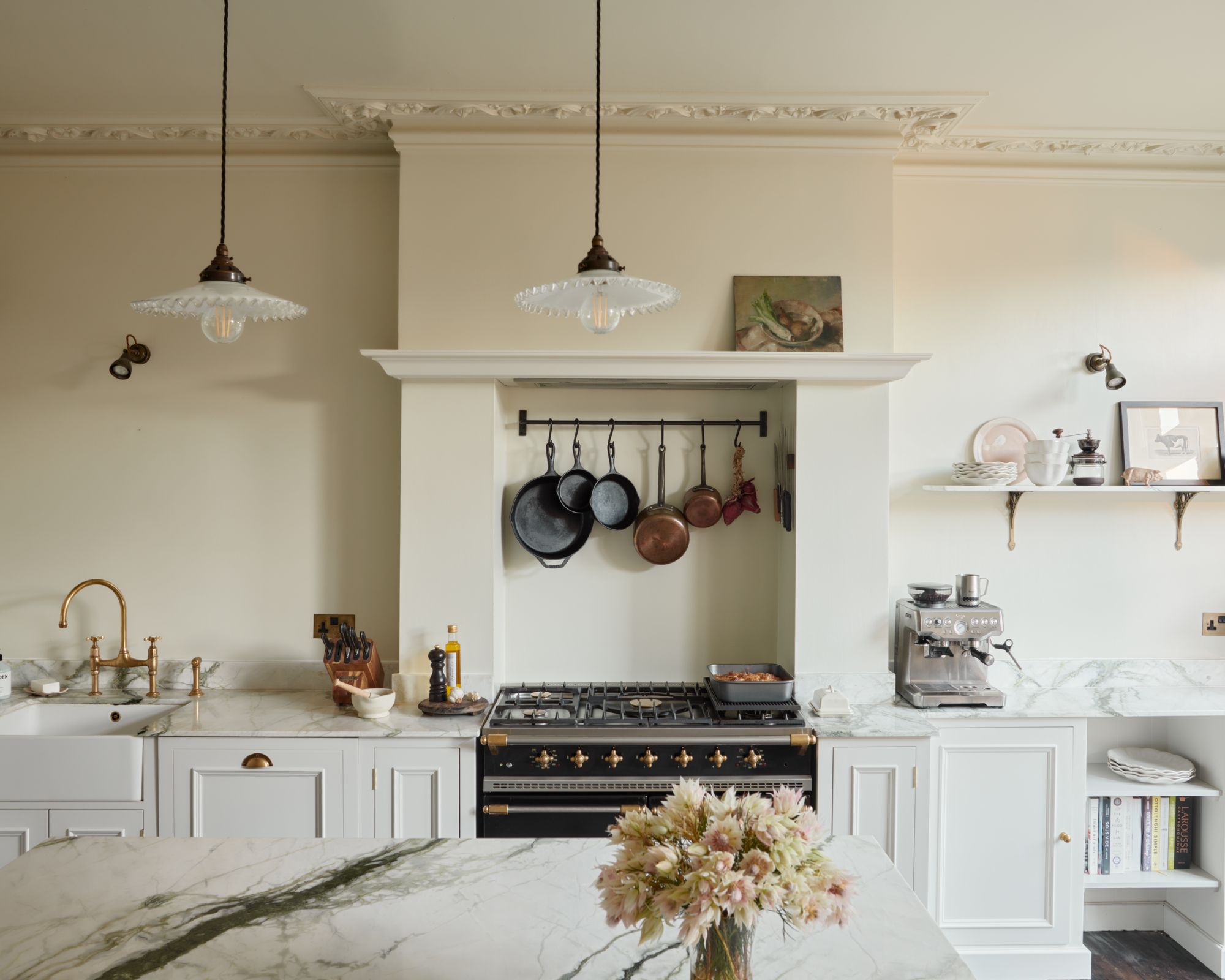 A white kitchen with pans hanging below a rangehood
