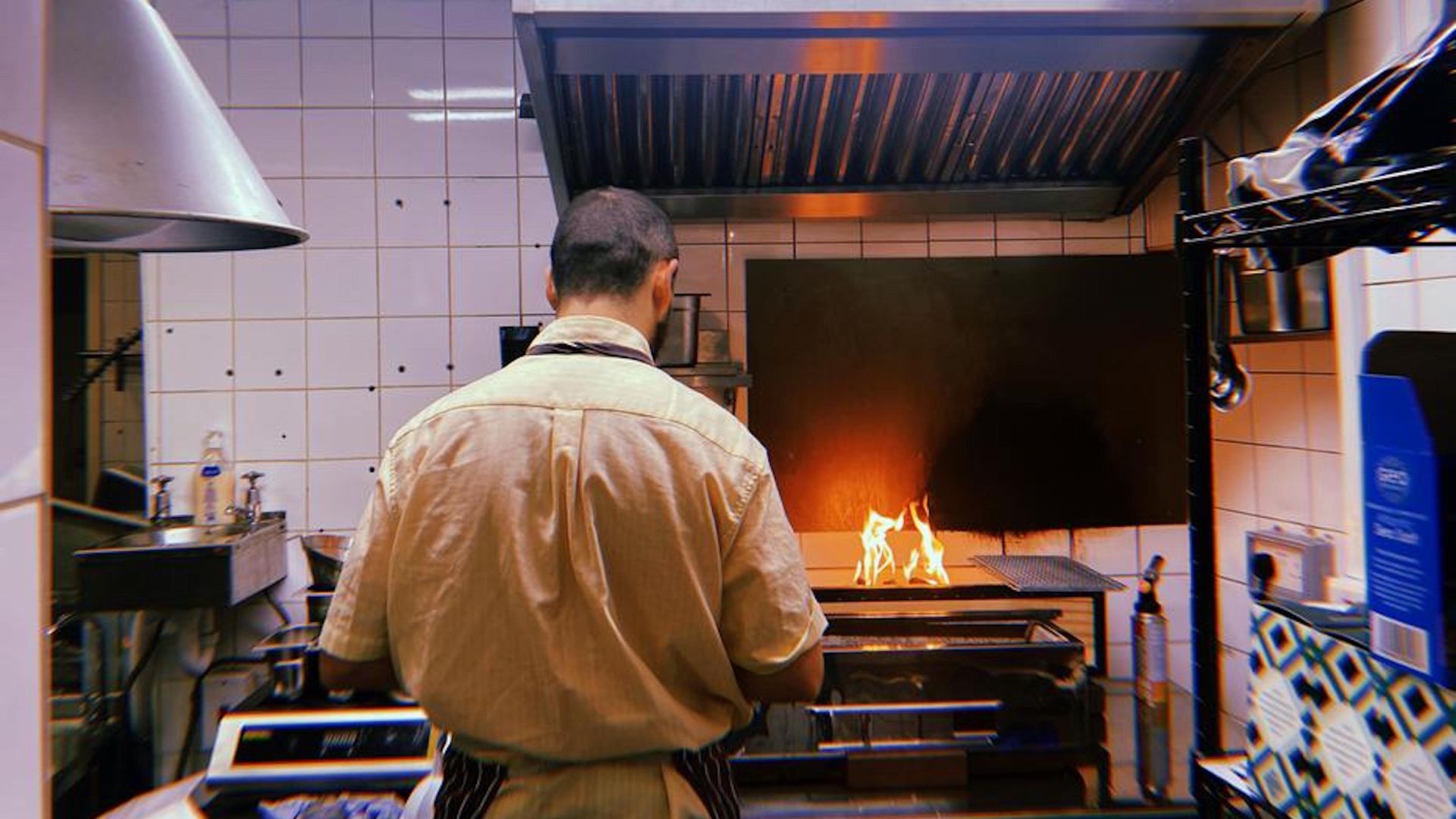 an image of a chef working at a flame grill