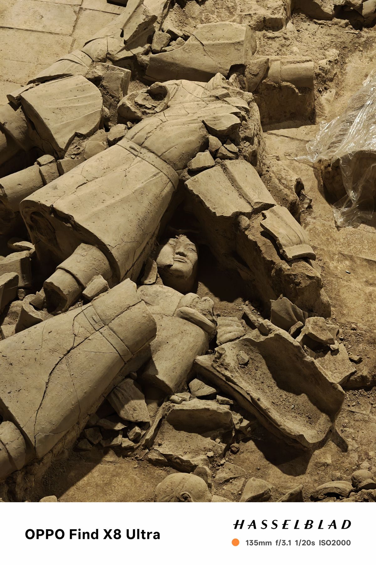 A statues face on the ground surrounded by ruins