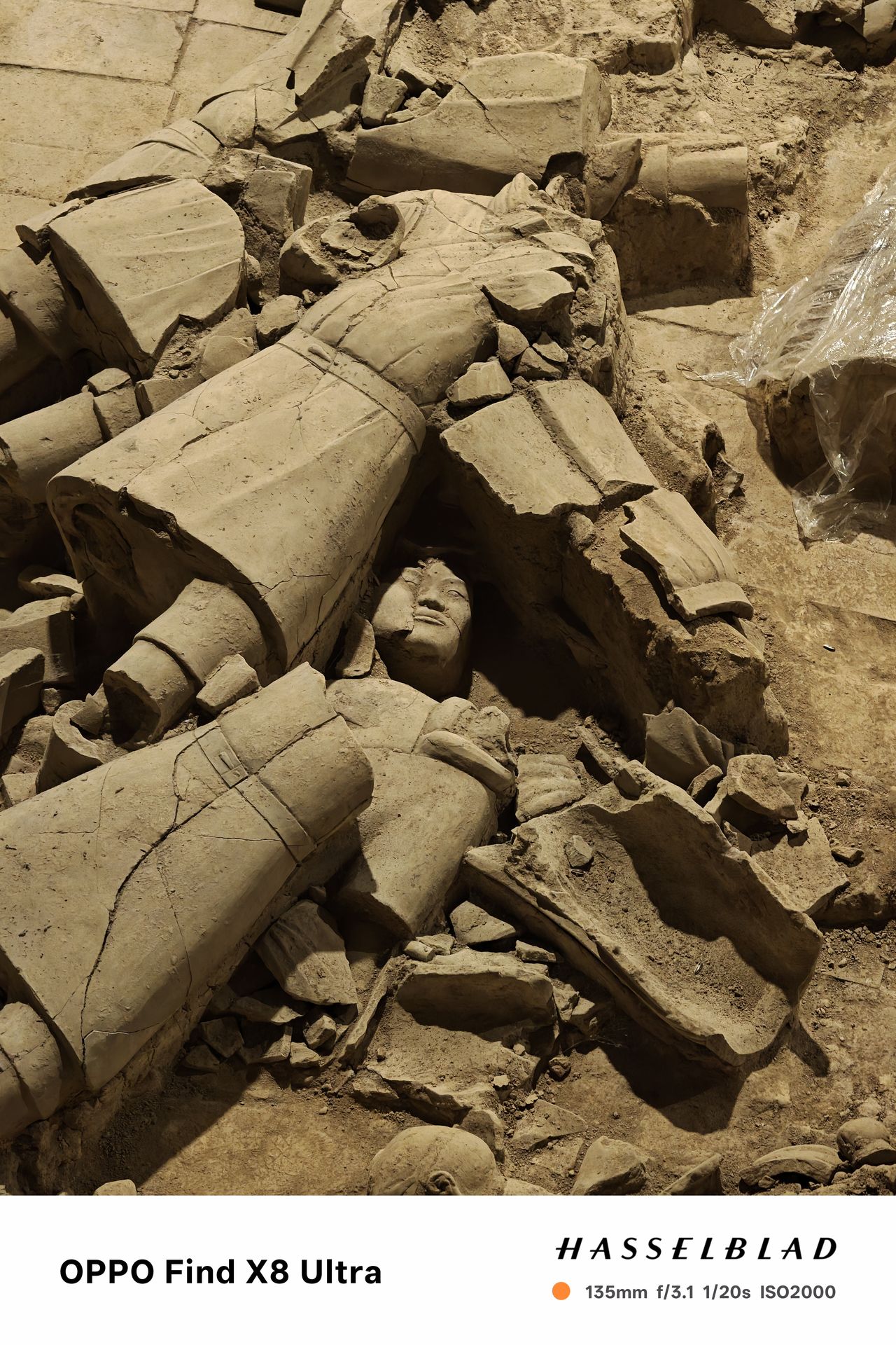 A statues face on the ground surrounded by ruins