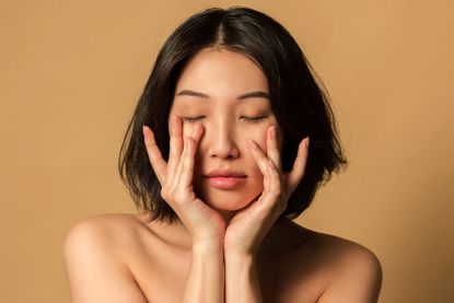 beauty portrait close-up of beautiful woman with clear skin on beige background studio shot
