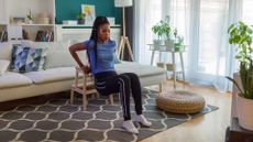 woman uses a stool for a tricep dip exercise at home