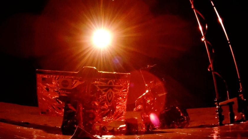 A photo of the Blue Ghost lunar lander on the surface of the moon bathed in a red light