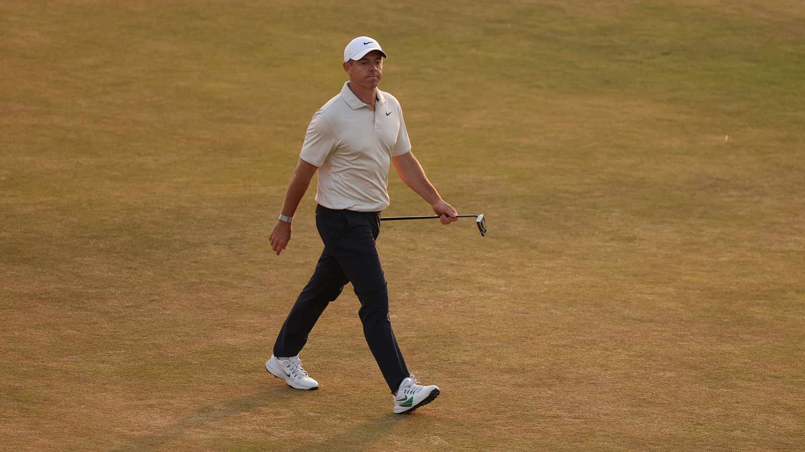 Rory McIlroy walks down the fairway holding his putter