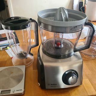 The Bosch MultiTalent 8 food processor and assorted accessories lined up on a wooden kitchen counter