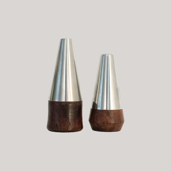 Wood and chome salt and pepper shackers with a conical shape against a pale grey background.
