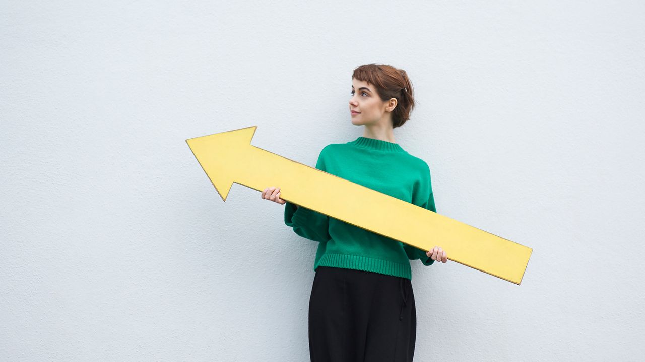 A woman holds a yellow arrow sign.