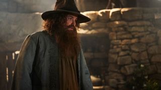 Rory Kinnear as Tom Bombadil in his hut during The Rings of Power season 2.