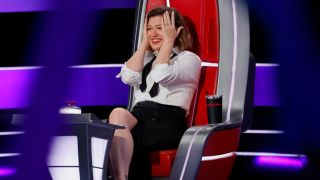 Kelly Clarkson puts her head in her hands during the Blind Auditions of The Voice Season 29.