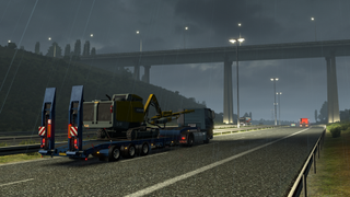 Relaxing PC game — Rolling down a rainy highway in Euro Truck Simulator 2, the player hauls some heavy construction equipment on their flatbed trailer.