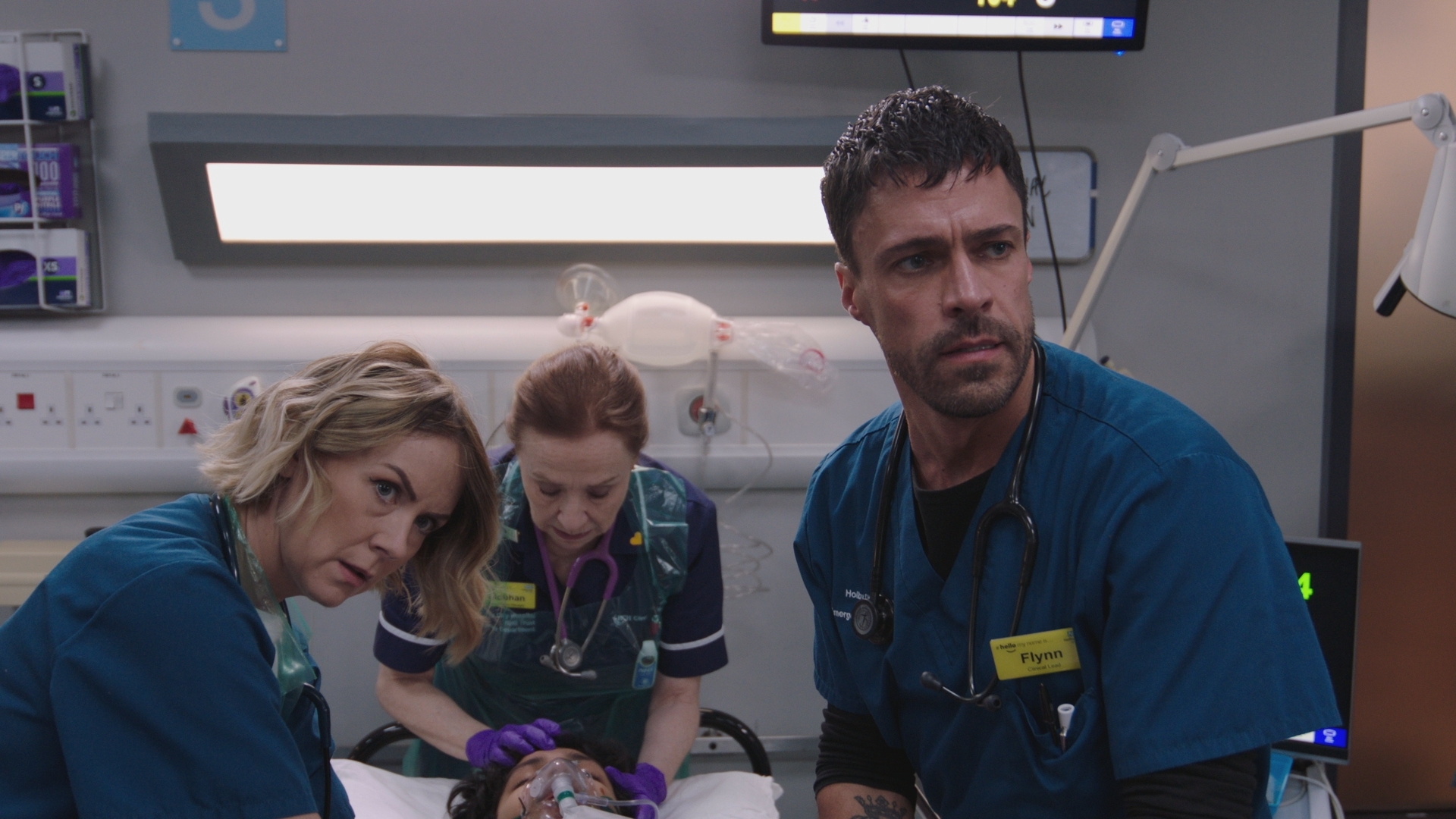 Jan informs senior medics Stevie Nash (Elinor Lawless), Siobhan and Flynn that more suspected overdose patients are on their way in, while they're frantically trying to save the life of a patient on a hospital bed.