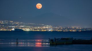 Августовское полнолуние по осетрам поднимается за горой Хортиатис и Салониками, Греция, 22 августа 2021 года.