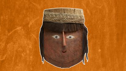 a red-painted wooden mask in the shape of a stylized human face with human hair attached