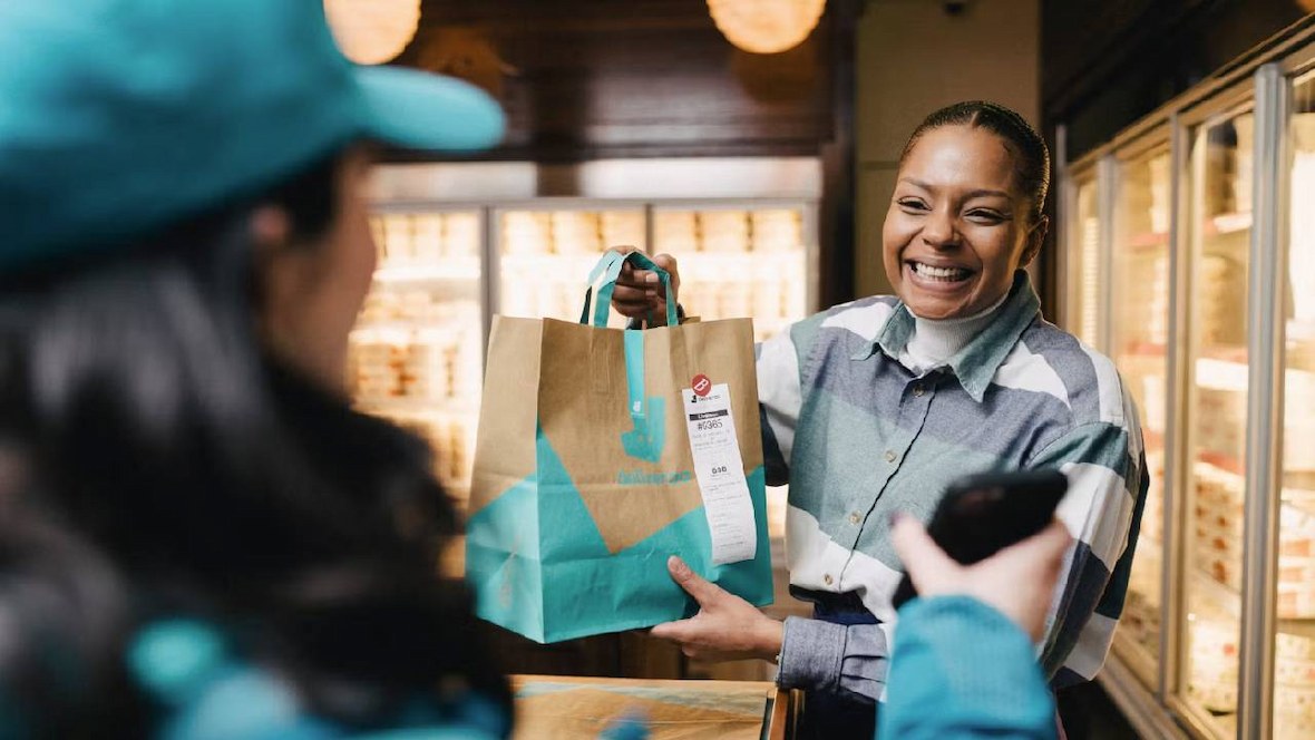 A woman picking up an order from Deliveroo.
