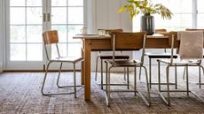 Textured brown carpet in dining room, dark wood dining table, wood and metal dining chairs, low hanging pendant lights, flowers on table