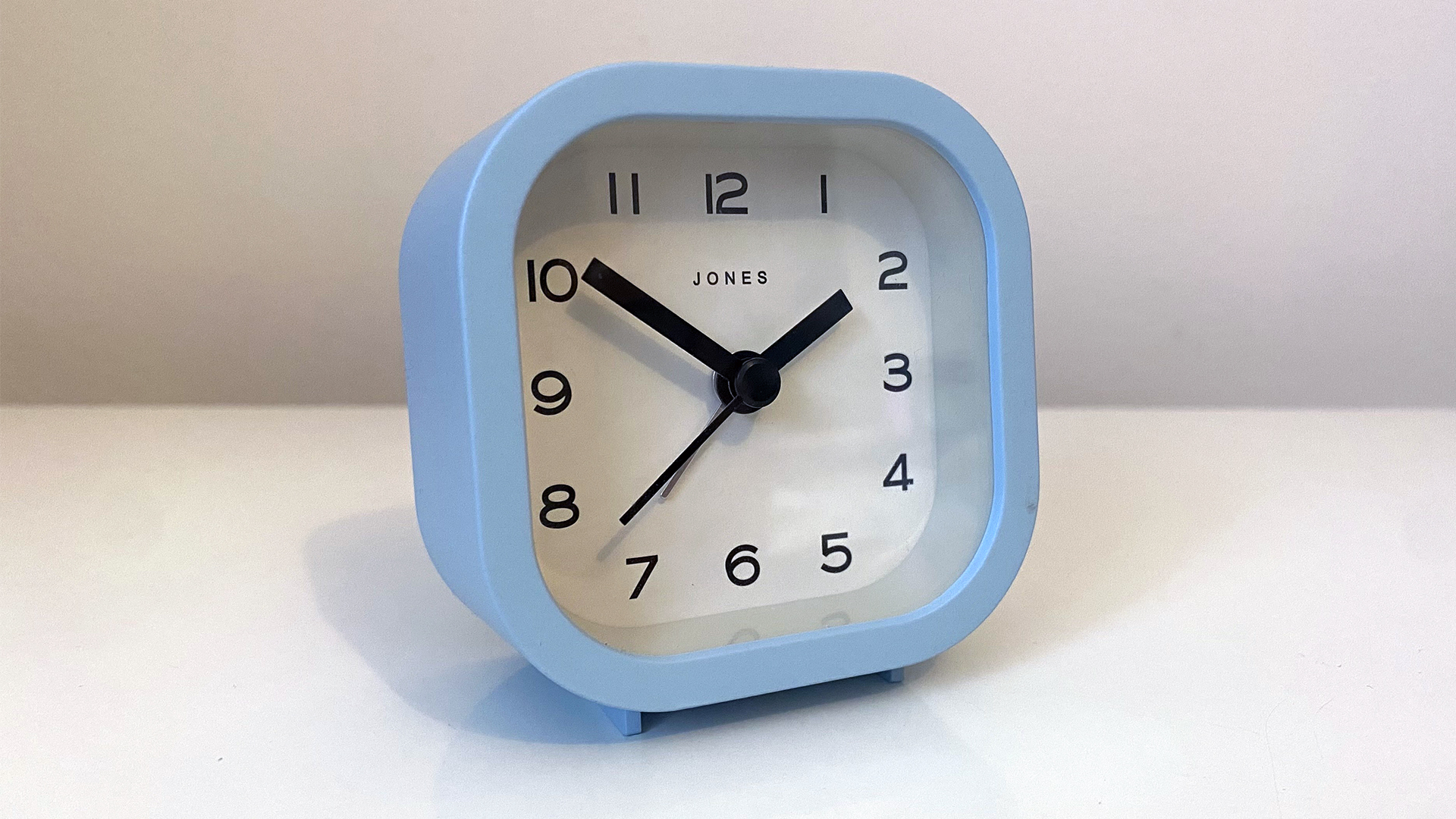 A blue alarm clock on a white nightstand