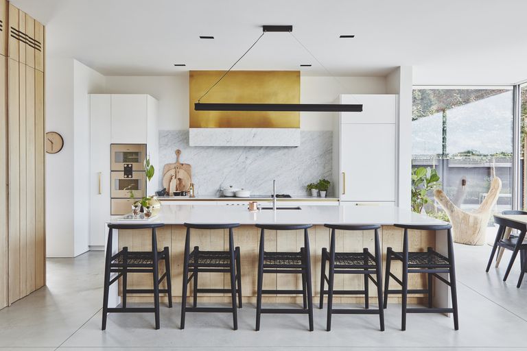 Designing a kitchen island in a large white kitchen with breakfast bar, black chairs and statement lighting.