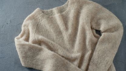 A wool sweater laid out on a flat blue surface