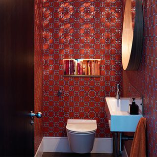 bathroom with red designed wall and commode