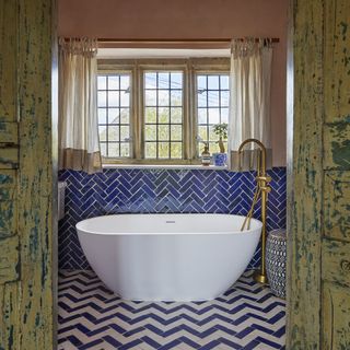 Bathroom with blue and white chevron tiled flooring and white bath