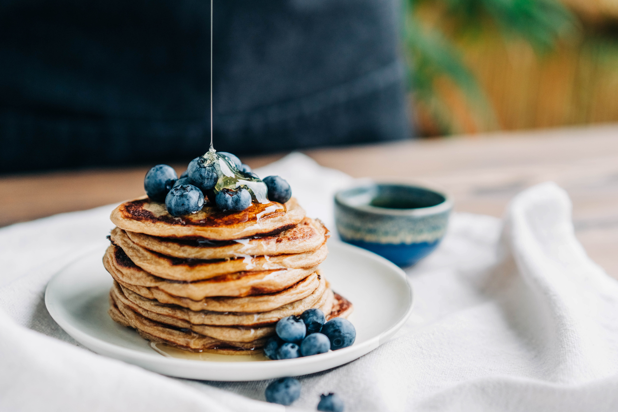 A stack of pancakes topped with blueberries and golden syrup.