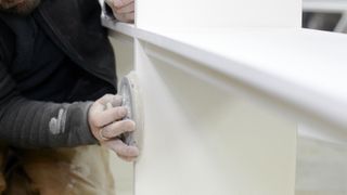 Hand sanding edge of painted MDF furniture