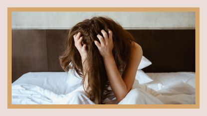 woman crying in bed with her hands in her head