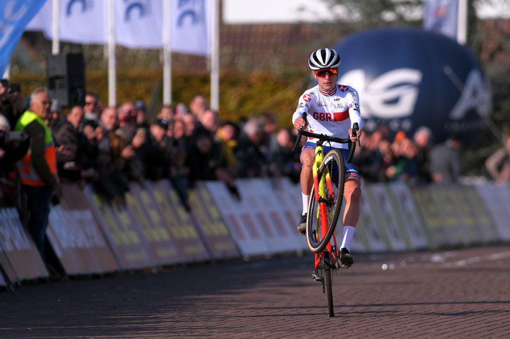 Tom Pidcock wheelies as he crosses the line