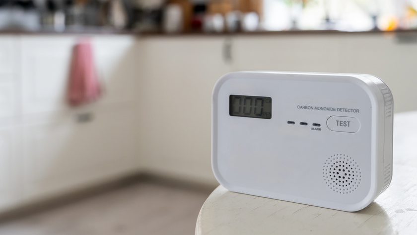 Carbon monoxide detector placed on a table with a kitchen blurred in the background