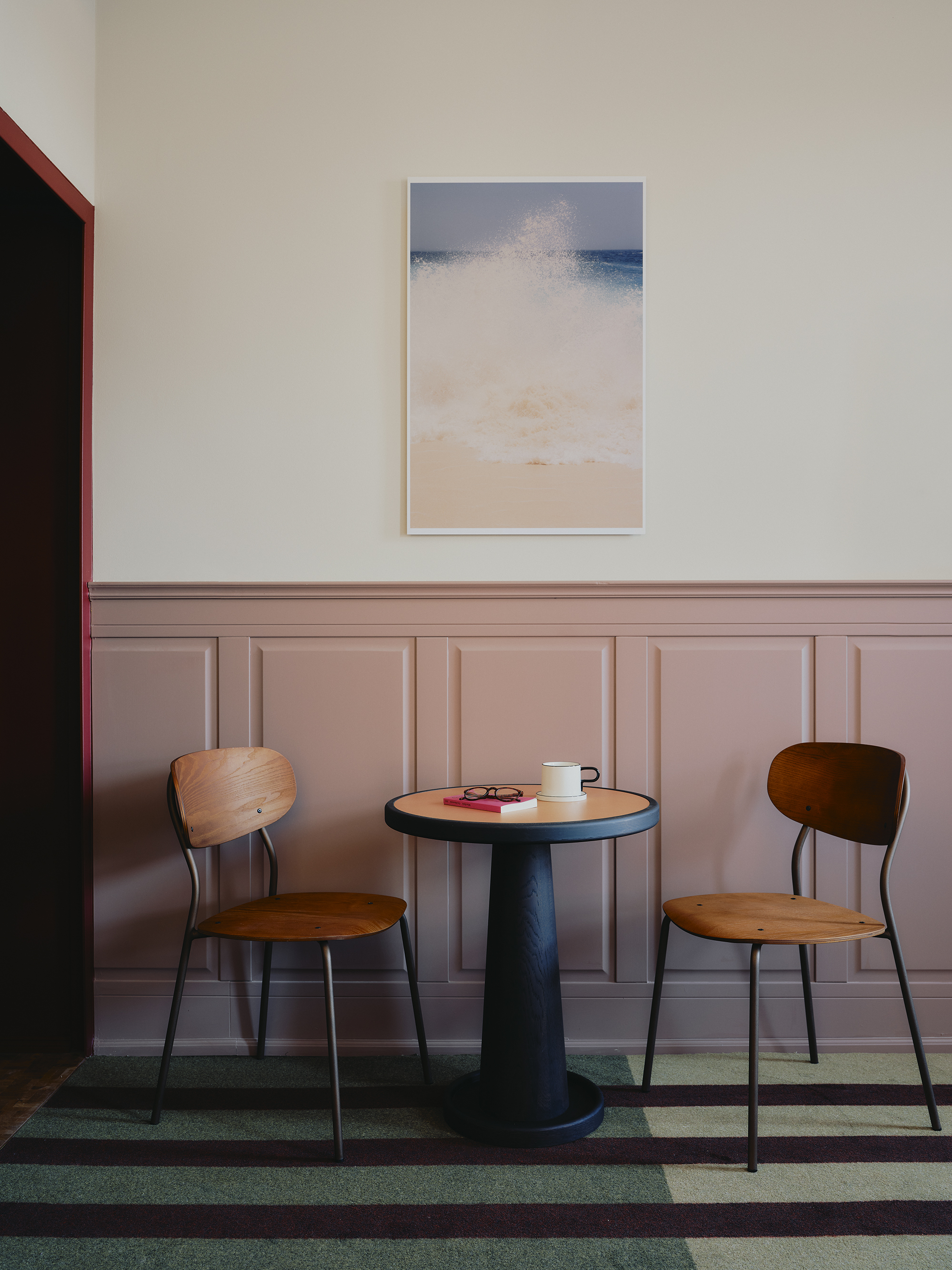 Interiors of a colorfully decorated hotel with a green, pink, and red palette, checkered or striped flooring, quirky, sculptural collectibles throughout, and lots of natural light.