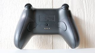 A picture of the back of the 8BitDo Ultimate Controller showing its remappable buttons and pogo pins for the charging dock