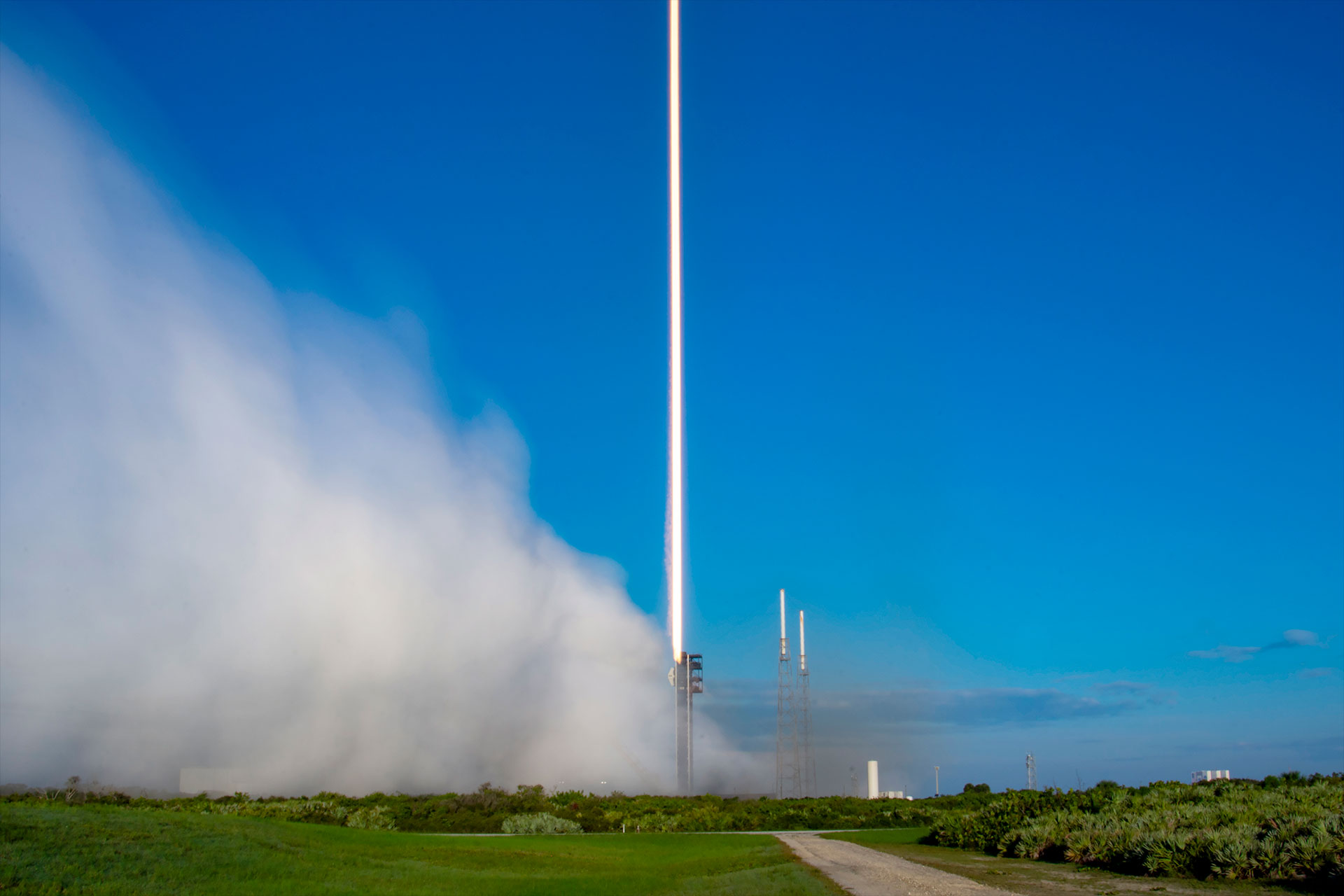 a time lapse image shows the streak of a rocket&#039;s thrust as it climbs to space against a blue sky