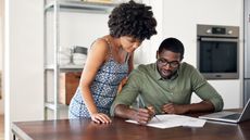 A young couple looks over life insurance paperwork at the kitchen table.