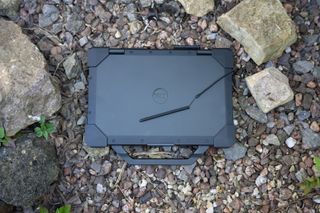 A black Dell Latitude 7330 Rugged Extreme laptop sitting on a rocky surface