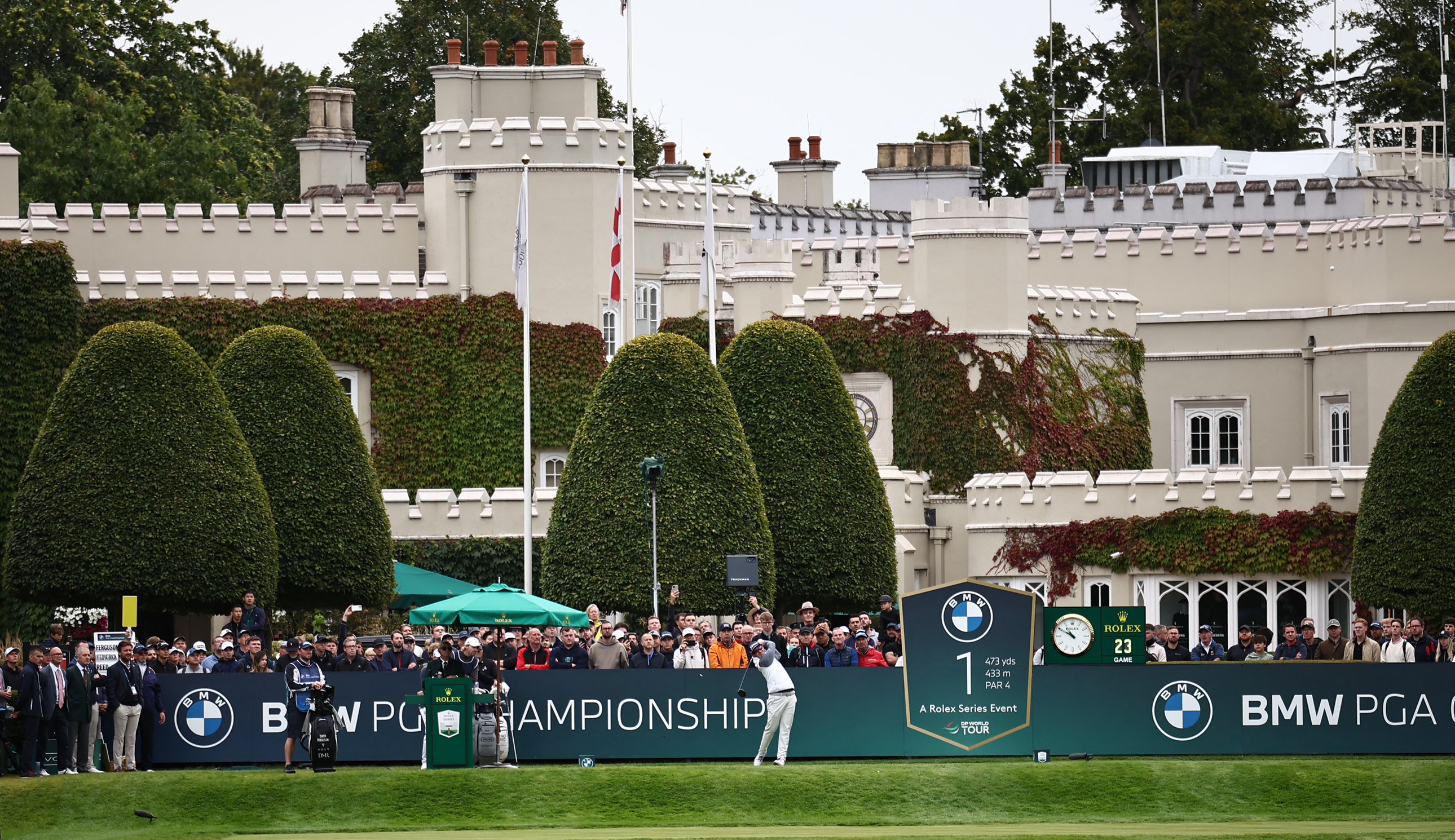 A golfer tees off in front of fans at Wentworth