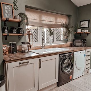 Green kitchen with washing machine and dryer under wooden counter by window