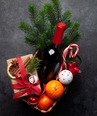 Christmas hamper filled with wine, foliage, presents, candy cane, ornaments