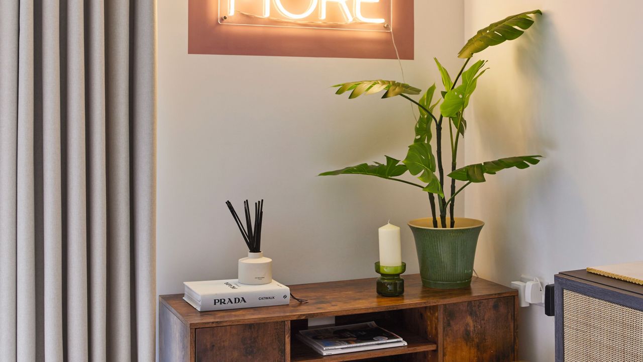 Dark wood console table with houseplant, candle, reed diffuser