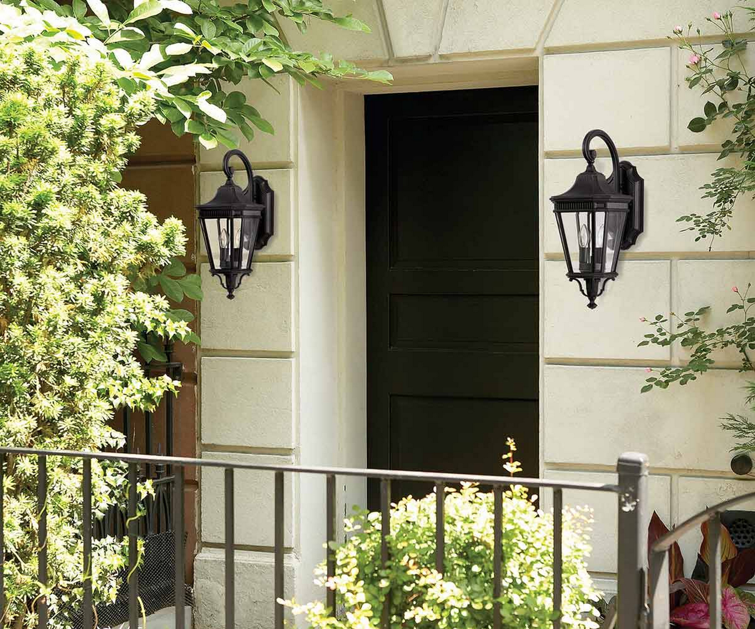 black metal and glass traditional wall lanterns on large entrance walls with metal railings in front