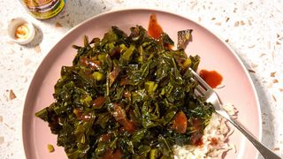 overhead shot of a mess of greens with rice and hot sauce