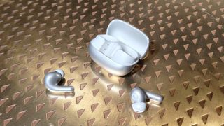 The Xiaomi Buds 5 Pro on a bronze table.