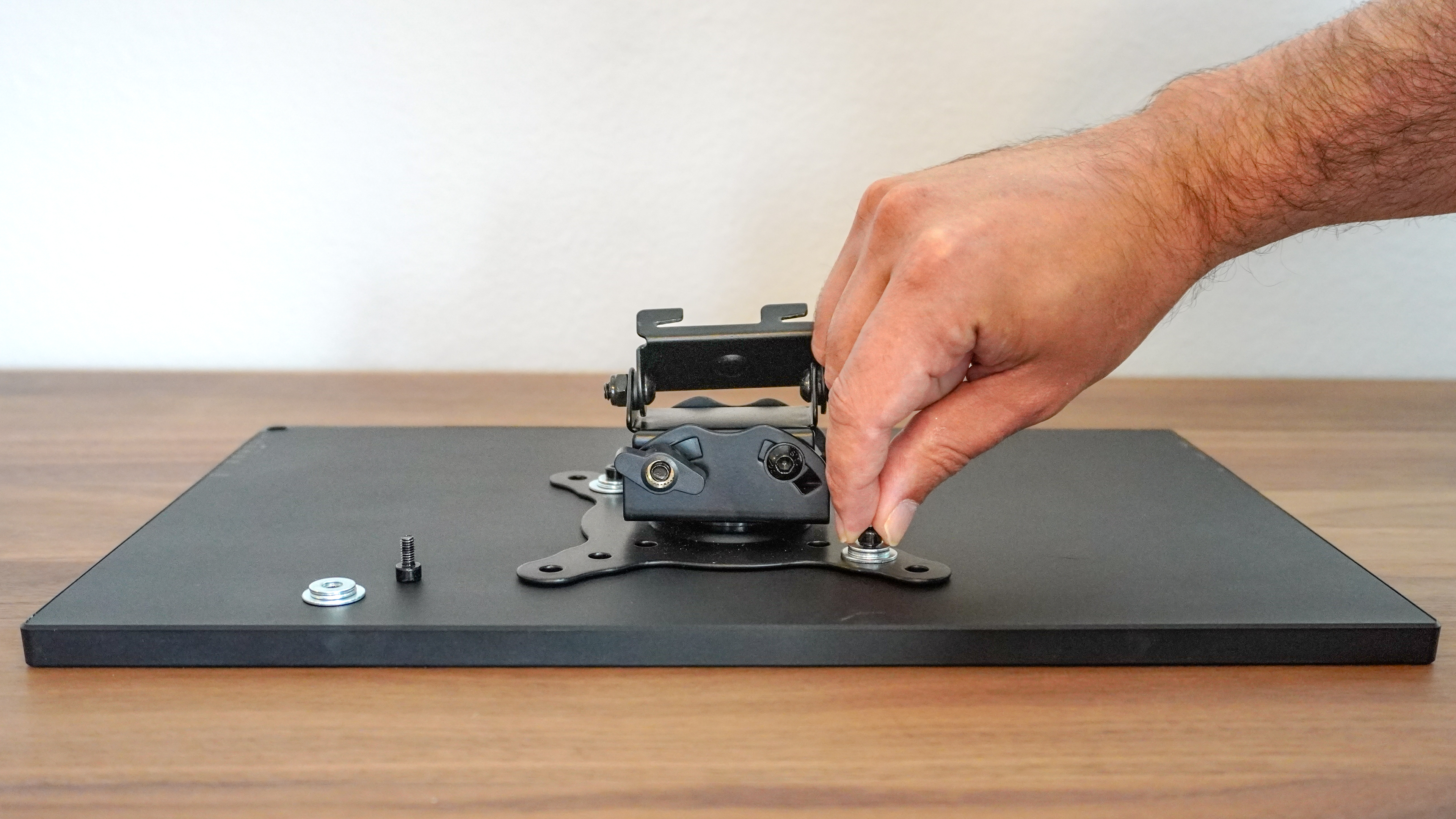 A person installing a VESA mount adapter on the back of a portable monitor