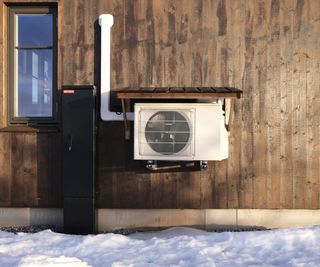 A heat pump attached to a timber clad energy efficient home with snow on the ground