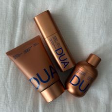 Dua Lipa x Augustinus Bader skincare products on a white linen background