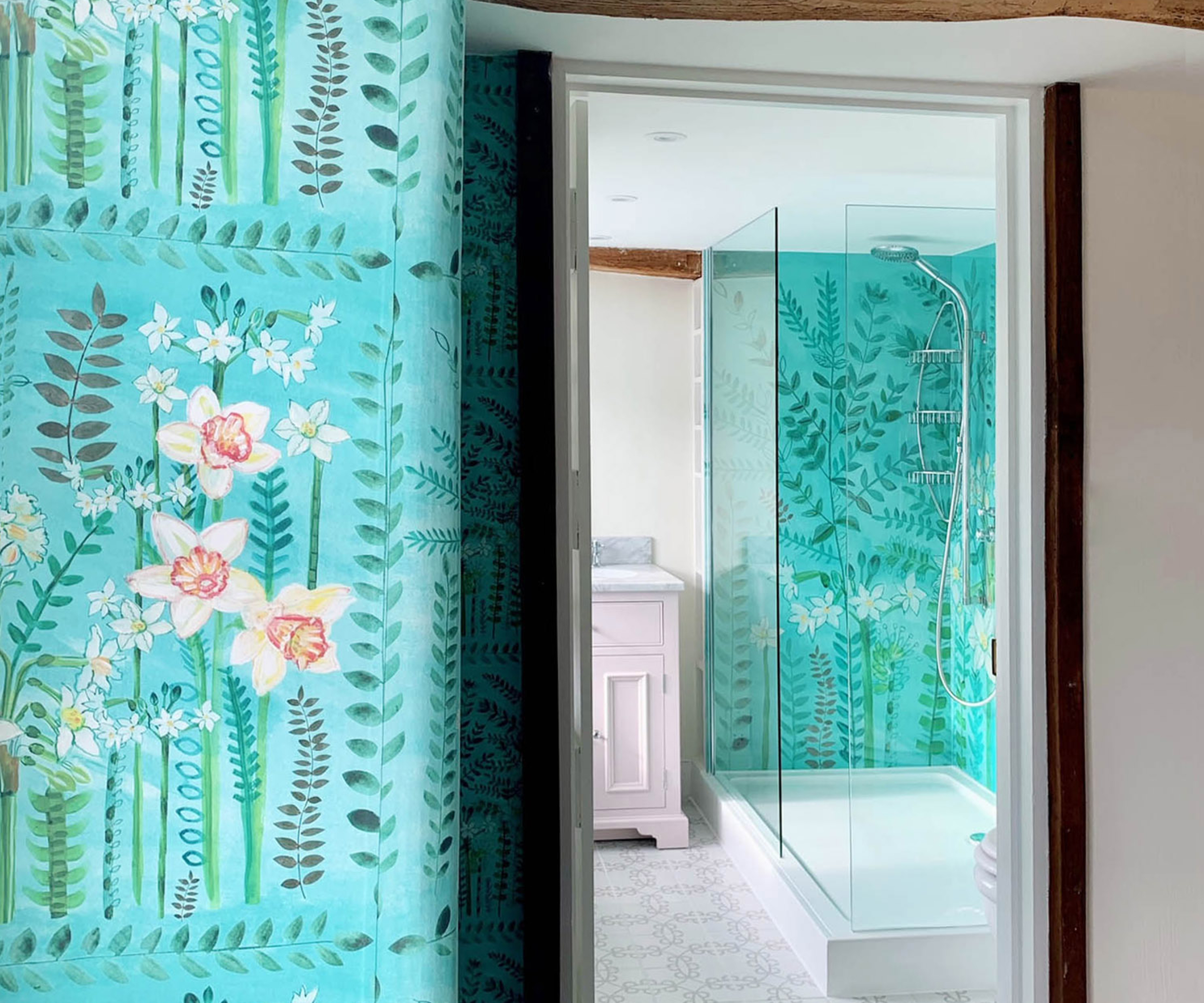 view into bathroom with wall panel in shower designed to match wallpaper on wall outside bathroom